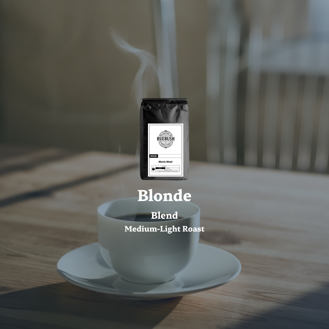 White cup of coffee with a steaming lid on a wooden table, accompanied by a bag labeled Blonde Blend