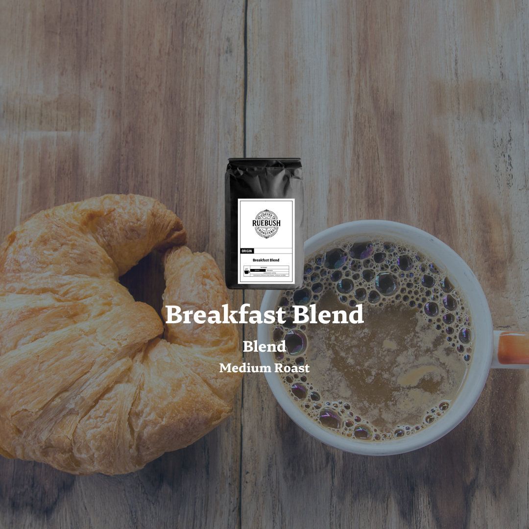 Mug of coffee with croissant and Breakfast Blend package on wooden surface