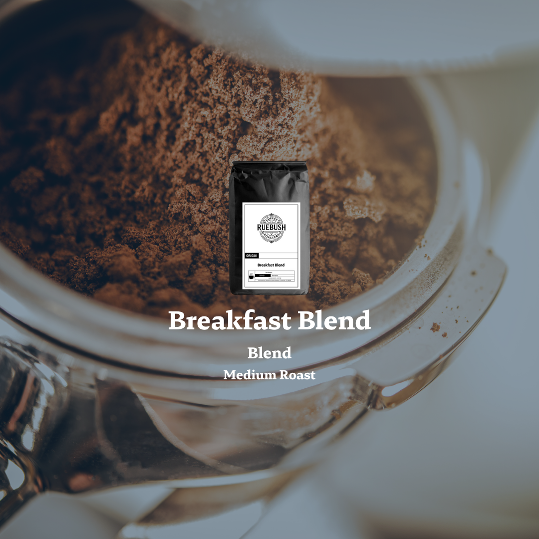 Coffee grinder with a Ruebush Coffee Roasters bag labeled Breakfast Blend on a blurred background
