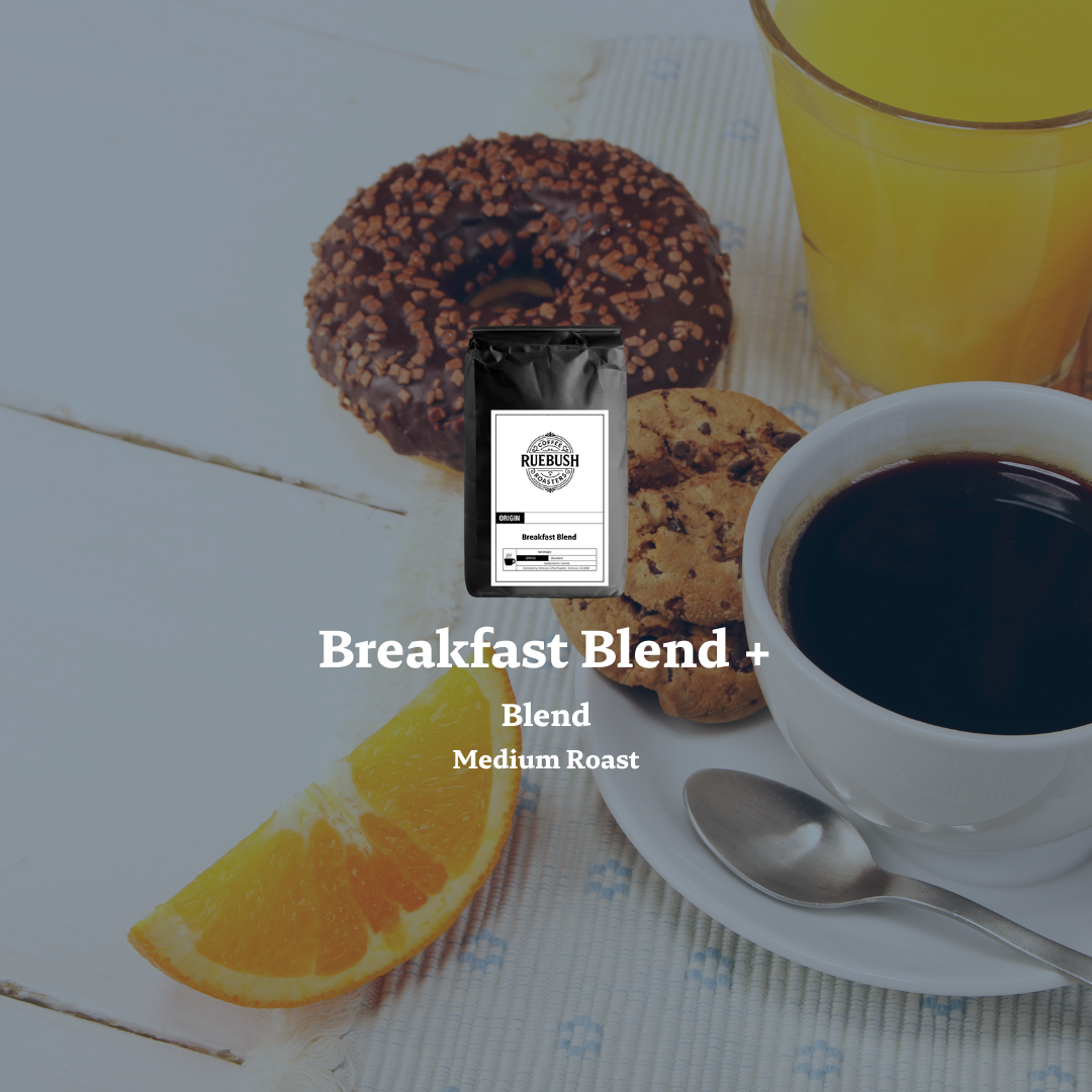 Breakfast scene with coffee, donuts, and a glass of orange juice on a white surface with an overlay of a bag of Ruebush Coffee Roasters Breakfast Blend +