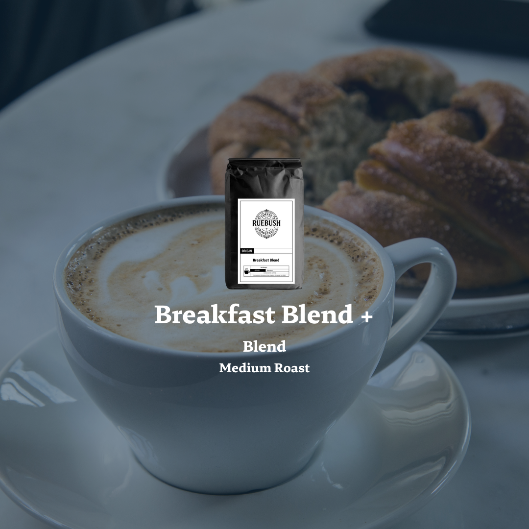Cup of coffee with a coffee bag labeled Breakfast Blend + on a table with pastries