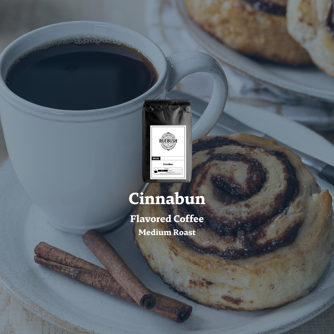 Cup of coffee with a cinnamon bun and cinnamon sticks on a plate, featuring a package labeled Cinnabun Flavored Coffee