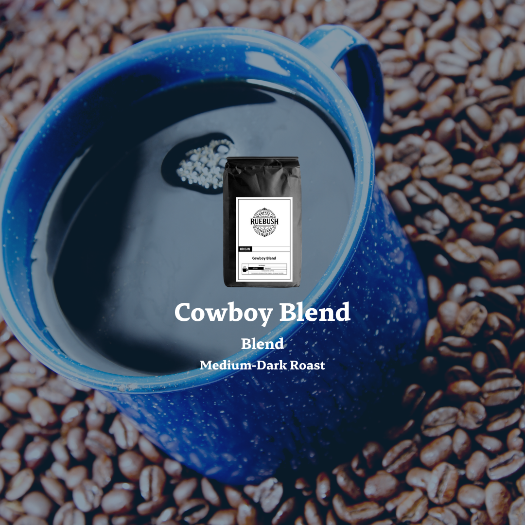Blue enamel mug with a coffee bag labeled Cowboy Blend on a background of coffee beans