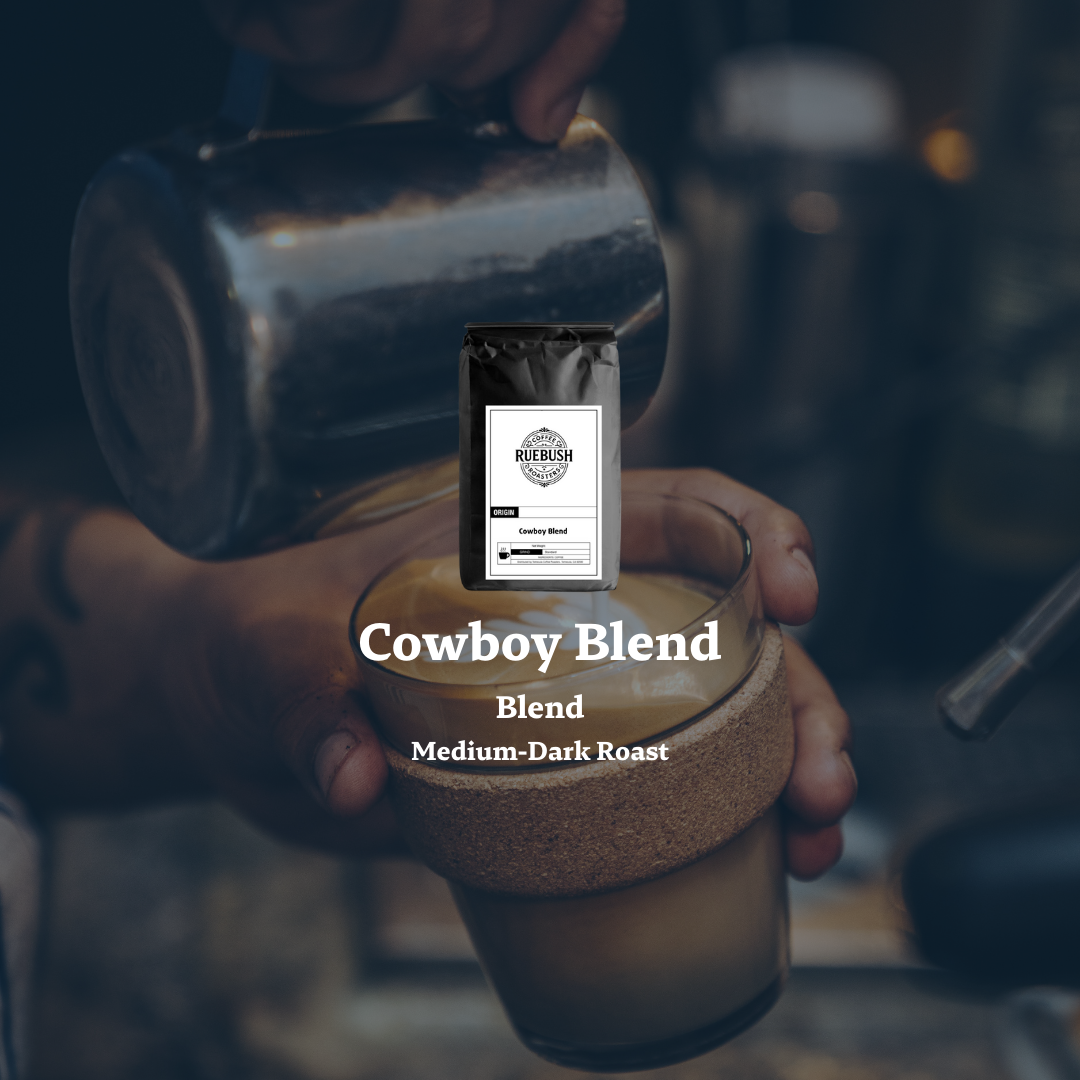 Person holding a coffee cup with a Cowboy Blend package on top, blurred background
