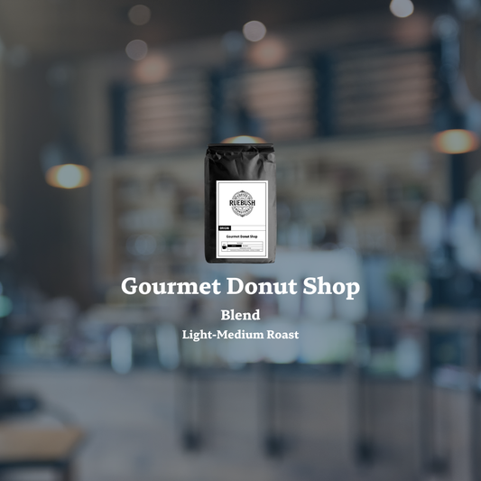 Coffee bag labeled Gourmet Donut Shop Blend by Ruebush Coffee Roasters with a blurred cafe background