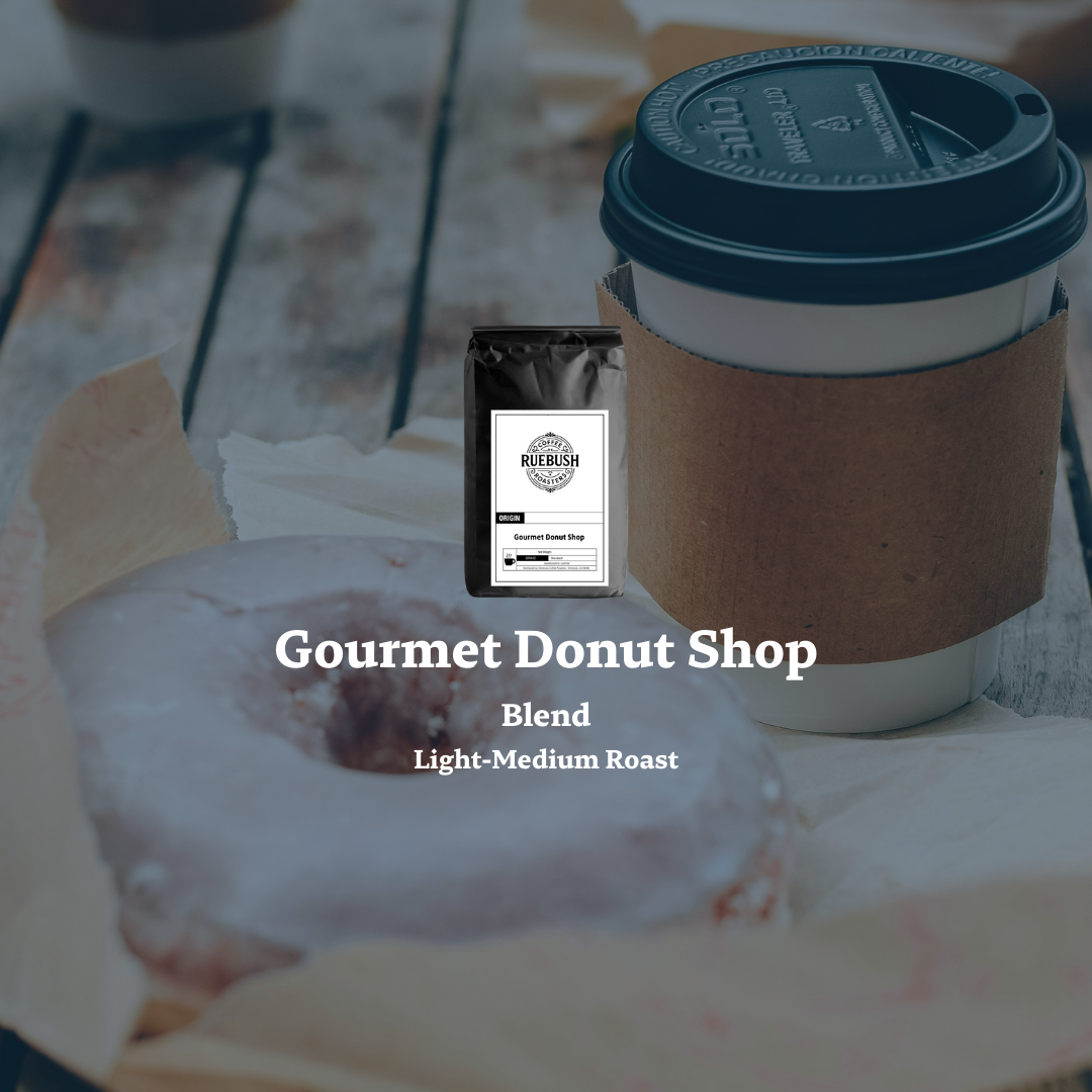 Coffee cup with a donut and Gourmet Donut Shop coffee bag by Ruebush Coffee Roasters on a table