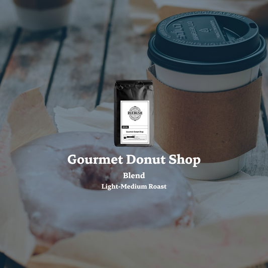 Coffee cup with a donut and Gourmet Donut Shop coffee bag by Ruebush Coffee Roasters on a table