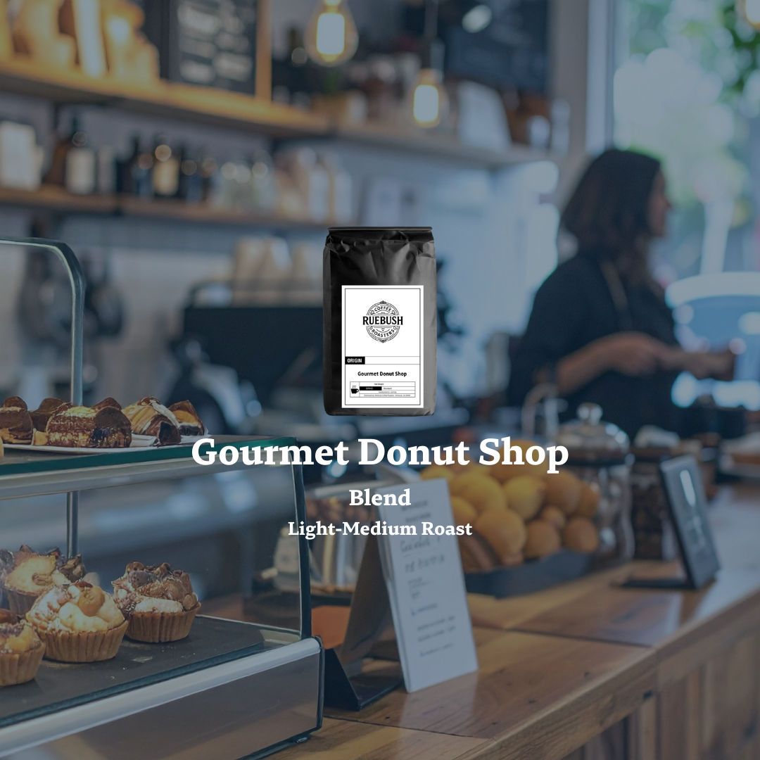 Gourmet donut shop with a coffee bag labeled Gourmet Donut Shop Blend by Ruebush Coffee Roasters on a blurred background