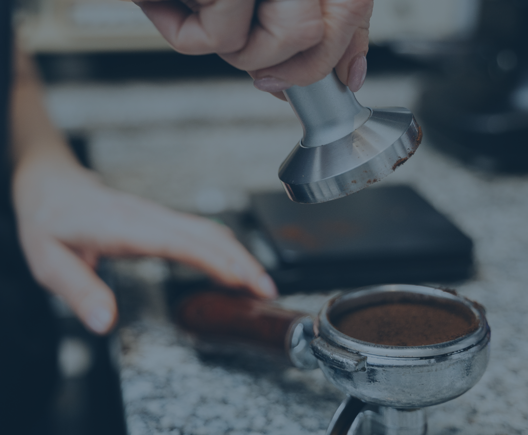 Hand using a tamp to compress Ruebush Coffee grounds in an espresso portafilter