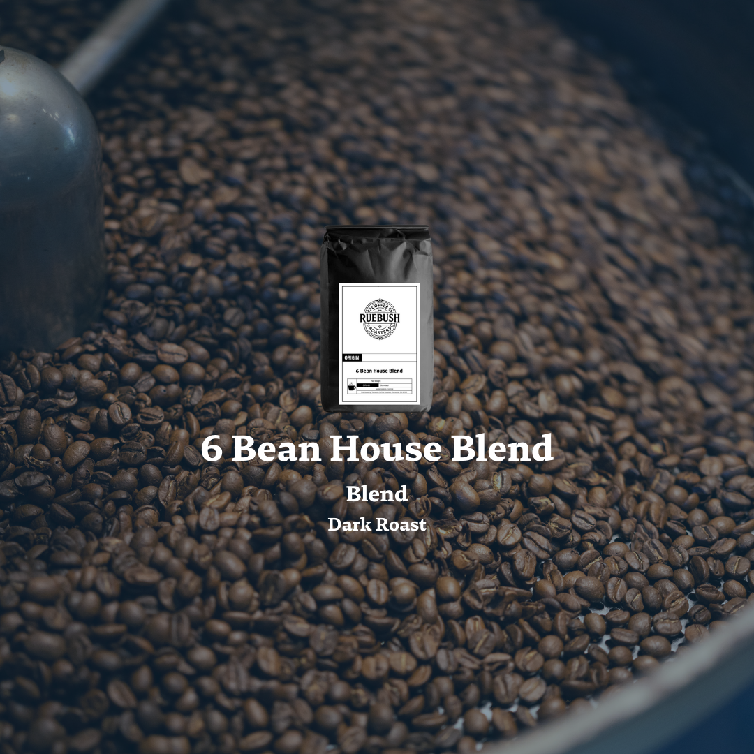Coffee bag labeled 6 Bean House Blend on a bed of coffee beans with a blurred background
