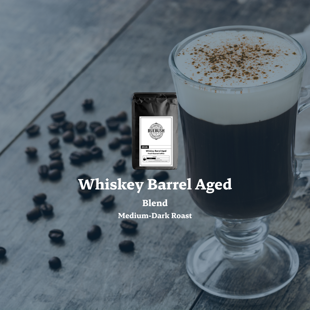 Glass of coffee with a package labeled Whiskey Barrel Aged Blend by Ruebush Coffee Roasters on a wooden surface