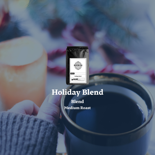 Blue mug with Holiday Blend coffee packaging by Ruebush Coffee Roasters on a blurred background