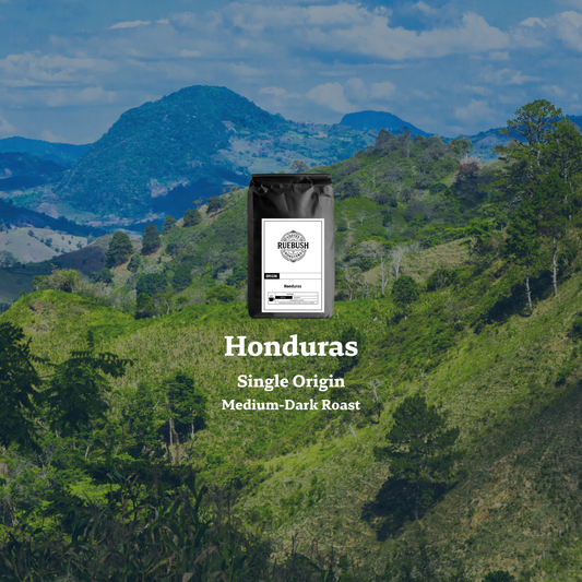 Coffee bag labeled Honduras Single Origin Medium-Dark Roast with a scenic background of green hills and mountains