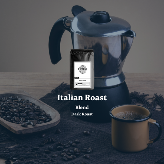 Moka pot with coffee beans, a mug, and a bag labeled Italian Roast Blend Dark Roast on a wooden surface