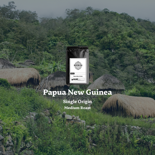 Coffee bag labeled Papua New Guinea with a scenic background of huts and greenery