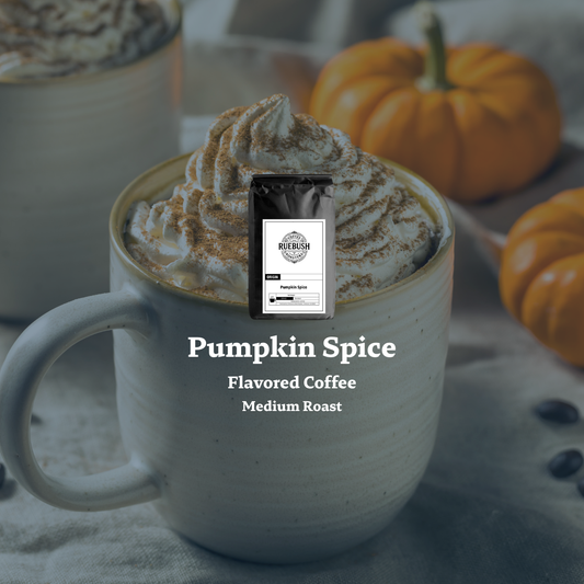 Pumpkin spice flavored coffee with a package labeled Ruebush Coffee Roasters on a white mug with whipped cream, surrounded by pumpkins