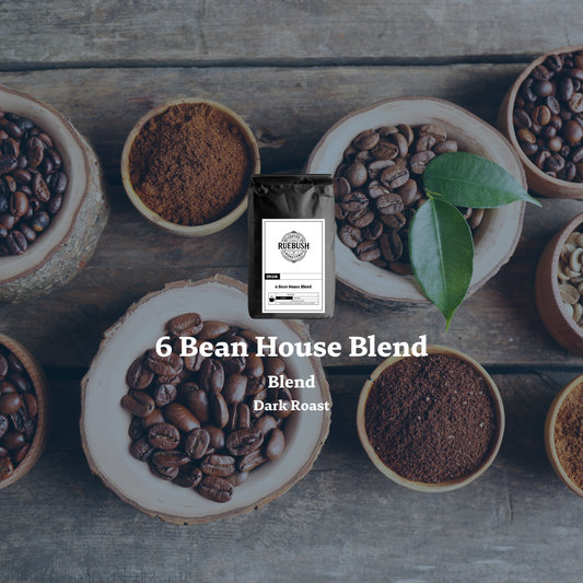 Coffee beans and grounds in wooden bowls with 6 Bean House Blend packaging on a wooden surface